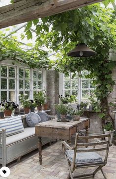 an outdoor room with lots of plants and furniture