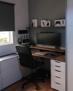 a desk with a monitor, keyboard and mouse on it in front of a window