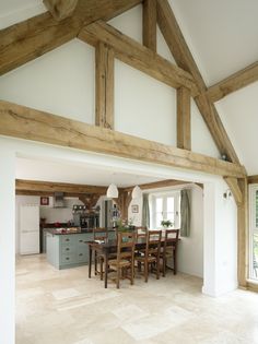 an open kitchen and dining room area with wood beams on the ceiling, white walls and floor