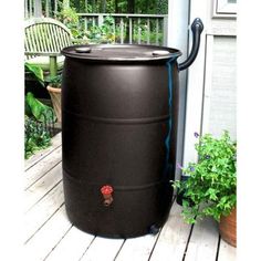 a large black barrel sitting on top of a wooden deck next to a potted plant