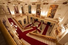 an ornate building with red carpeted stairs and chandeliers on either side of the staircase