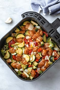 a casserole dish filled with meat, vegetables and sauce on a white table