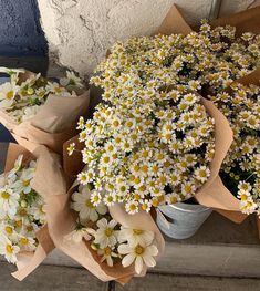 several bunches of daisies are sitting on the ground next to each other and wrapped in brown paper