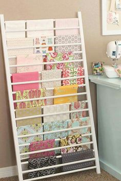 a white shelf filled with lots of different types of wrapping paper next to a sewing machine