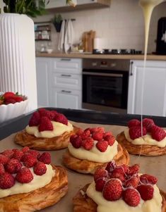 four croissants topped with whipped cream and raspberries on a counter