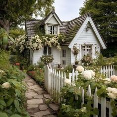 a white house surrounded by flowers and greenery