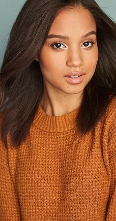 a woman with long hair wearing an orange sweater