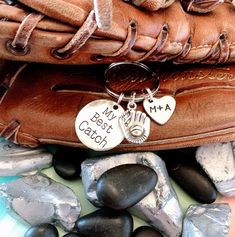 a baseball mitt with two charms on it sitting next to some rocks and stones