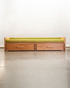 a wooden bench with two drawers on it's sides and a green seat cushion