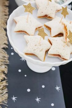 star shaped cookies on a white plate with gold glitter stars in the middle and black table cloth