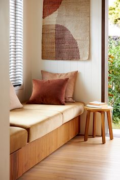 a wooden bench sitting next to a window covered in pillows and throw pillow covers on top of it