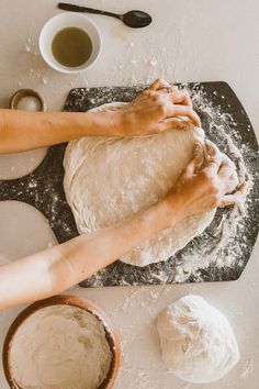 two hands are kneading dough on a table