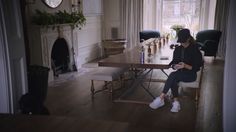 a woman sitting at a table looking at her cell phone in the middle of a room