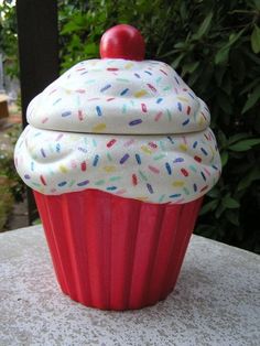 a red cupcake with white frosting and sprinkles sitting on top of a table