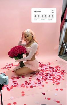 a woman sitting on the ground with flowers in front of her and a camera behind her