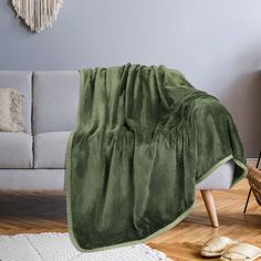 a living room with a gray couch and green blanket on the floor next to it