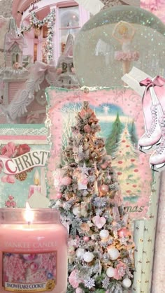 a small christmas tree next to a lit candle in front of a pink and white wall