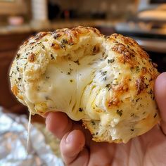 a hand holding a piece of bread with cheese and herbs sprinkled on it