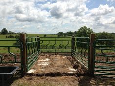 an open gate in the middle of a field with grass and dirt on both sides