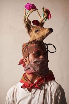 a man wearing a deer mask with flowers on his head