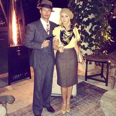 a man and woman standing next to each other in front of a tree at night