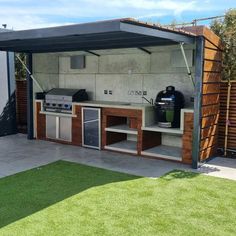 an outdoor kitchen is built into the side of a building with grass in front of it