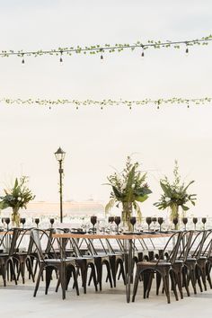 tables and chairs are set up for an outdoor event with string lights strung over them