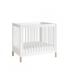 a white crib with wooden legs and a mattress on the bottom floor, in front of a white background