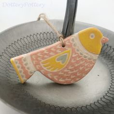 a ceramic bird ornament hanging from a wire on top of a metal tray