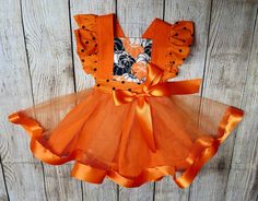 "Fall/Thanksgiving/Halloween/Pumpkin Flutter Pinafore Dress An adorable Fall Themed Dress for little girls with flutter (ruffled) sleeves and a criss cross back. Tulle and Satin orange ribbon to add a touch of elegance. This dress is perfect for Pumpkin patch professional photos, Photography Holiday photos, a Halloween Costume, or formal family get together.  Dress is handmade using 100% Cotton, Orange tulle and Satin Ribbon. Polka Dot sleeves are gathered by hand, Orange Straps crisscross in the back, Waistband has elastic on the back half to make the dress an easy pull on over the Childs head. The Skirt part is attached to the bodice after being gathered by hand. It is made up of solid orange 100% cotton and a tulle overlay. The tulle has satin (1 1/2\") orange ribbon sewed onto the bott Get Together Dress, Toddler Pageant Dresses, Monogrammed Burp Cloths, Girls Fall Dresses, Pumpkin Dress, Pumpkin Outfit, Tulle Party Dress, Thanksgiving Dress, Personalized Baby Shower Gifts