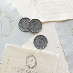 two silver coins sitting on top of some old envelopes next to paper and stamps