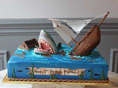 a birthday cake decorated to look like a boat with a shark's mouth and teeth