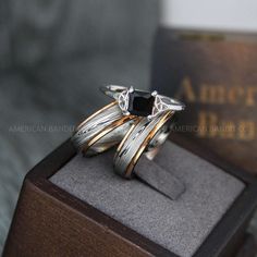 two silver rings sitting on top of a wooden box