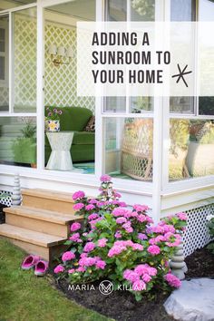 a porch with pink flowers and green furniture in the sunroom, next to a flower bed