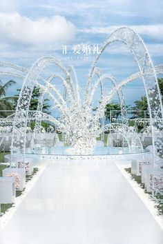 an outdoor ceremony setup with white flowers and arches in the center, surrounded by clear chairs