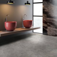 two red bowls are sitting on a wooden shelf in front of a large wall mirror