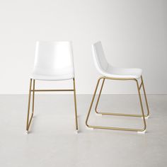 two white chairs sitting next to each other on top of a cement floor in front of a white wall