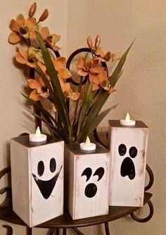 three wooden blocks with faces painted on them and flowers in the middle, sitting on a table