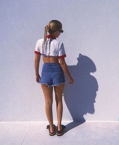 a woman standing against a wall with her back to the camera