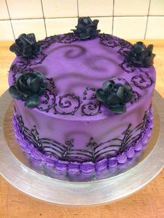 a purple cake sitting on top of a wooden table next to a white tile wall