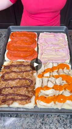 a woman standing in front of a tray filled with different types of hotdogs