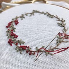 a close up of a piece of embroidery on a white cloth with red flowers and leaves