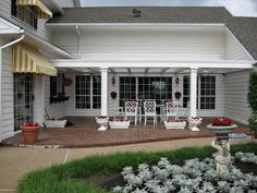 a white house with red and yellow awnings on it's front porch