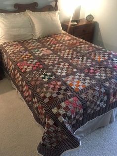 a bed with a quilt on top of it in a bedroom next to a night stand