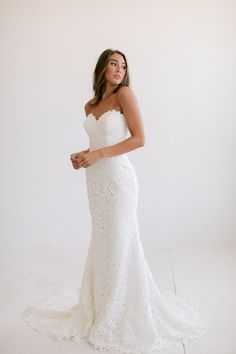 a woman in a white dress posing for the camera with her hand on her hip