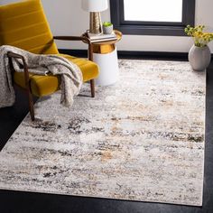 a yellow chair sitting on top of a black floor next to a white and gray rug