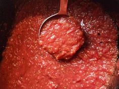 a spoon in a pot filled with red sauce