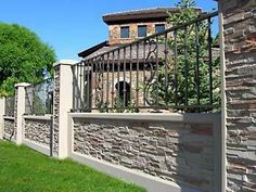 a stone wall and gate in front of a house