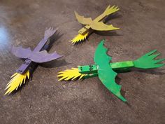 three birds made out of construction paper sitting on the ground with measuring tape around them