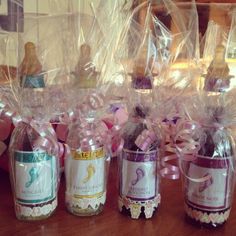 three small jars filled with candies and wrapped in cellophane, sitting on a table